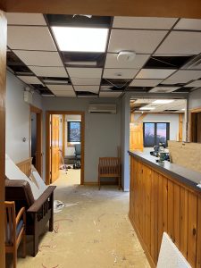 Hallway view of construction with a tall reception desk on right and two open rooms on the left and right.