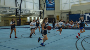 A group of young teen girls playing basketball at a basketball summer camp in Orono Maine