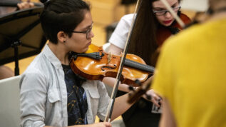 A student playing the violin at a music summer camp in Orono Maine