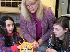 A female instructor helps two female students at an engineering summer camp in Orono Maine