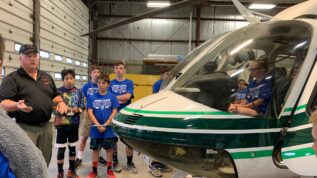 A group of young kids looking at a helicopter during the Maine Summer Transportation Institute summer camp in orono Maine