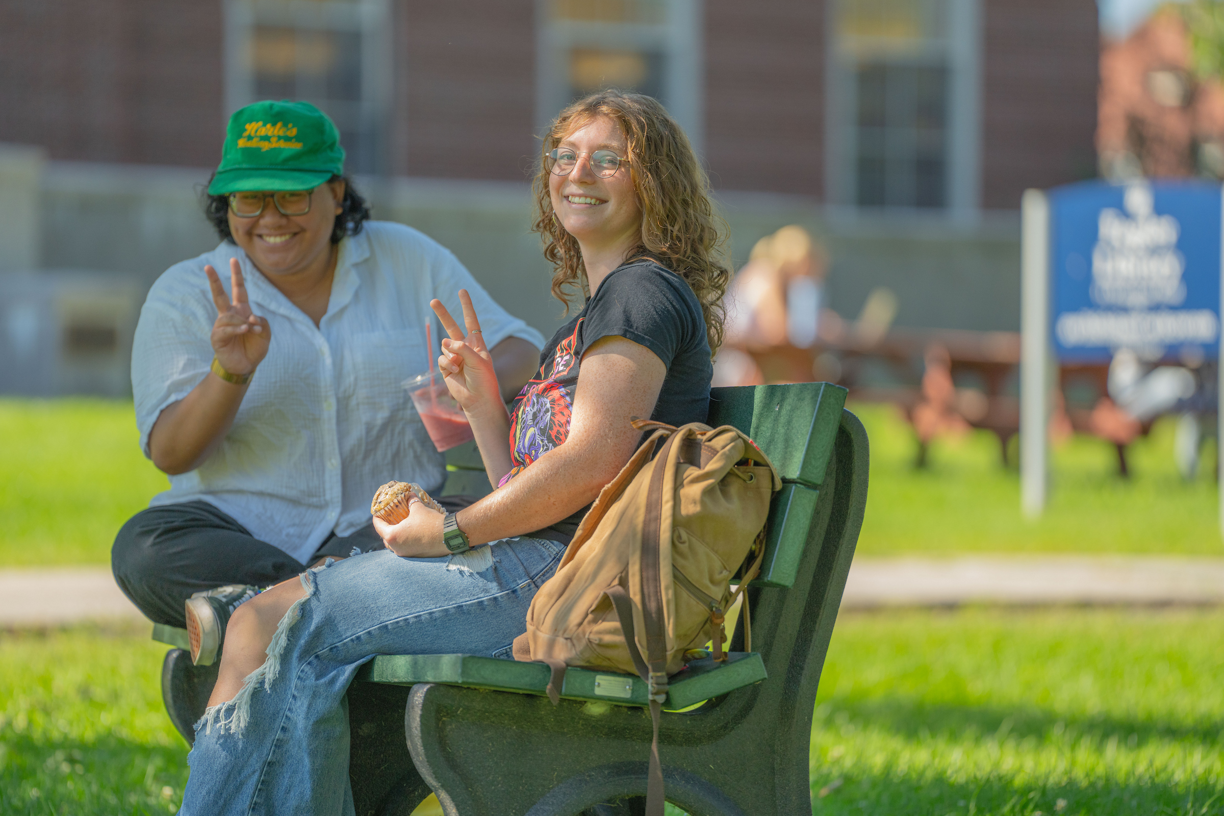 Two students smailing and making a peace sign on campus