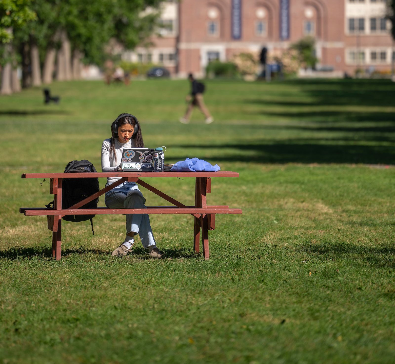 Student working on laptop outdoors on the UMaine mall