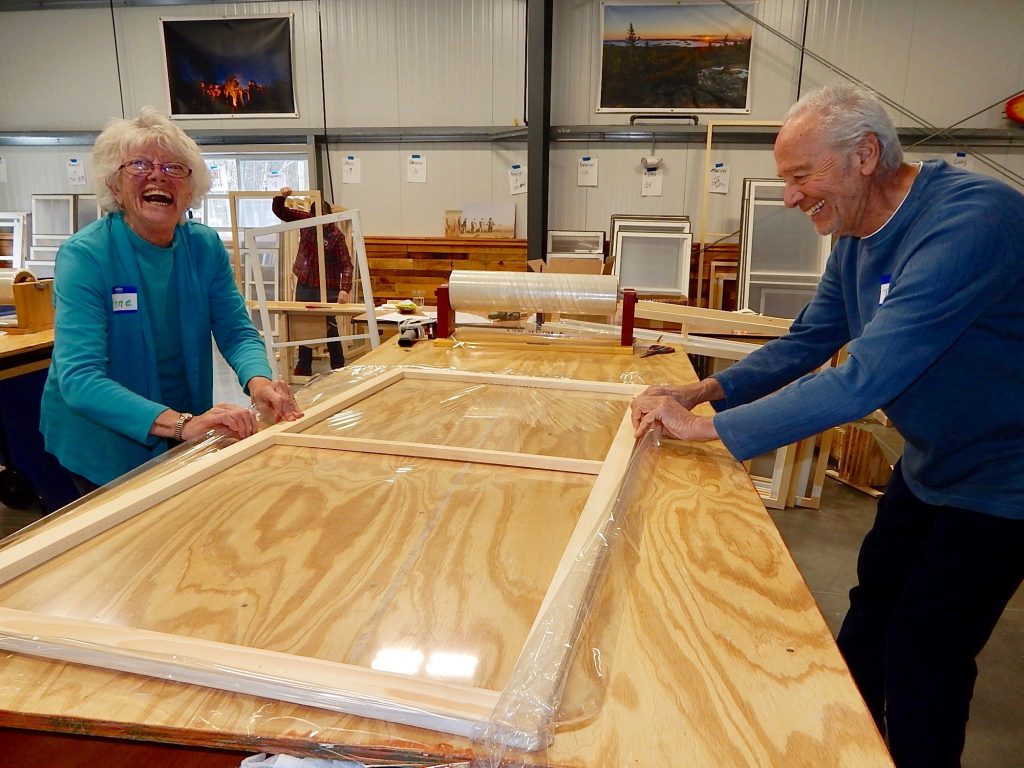 Window insert build volunteers stretching plastic over a window insert frame.