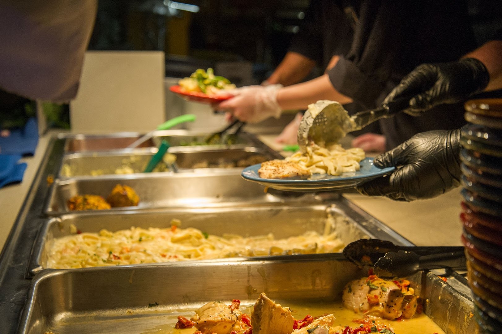 UMaine dining worker scooping pasta onto a plate.