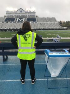 A zero-waste team member posing in front of the Alfond Stadium field