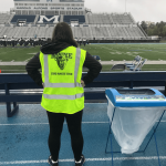 Student wearing Zero Waste Team safety vest looking out to football field