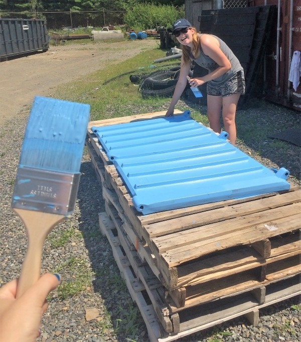 Students painting a bin lid blue.