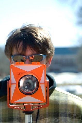 young man looking through surveying instrument