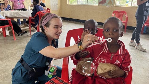 Nursing student blowing bubbles with child in Tanzania