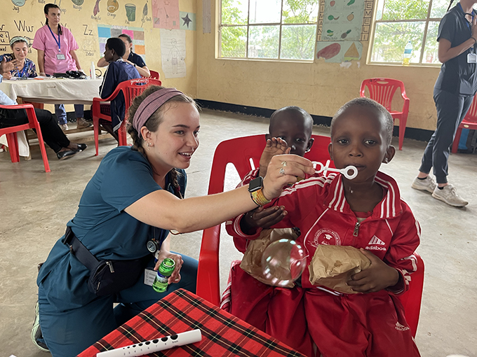 Nursing student blowing bubbles with child in Tanzania