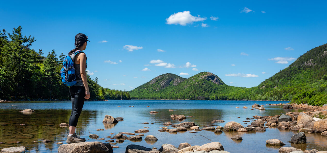 A female hiker exploring Jordan Pond in Acadia National Park, Maine.