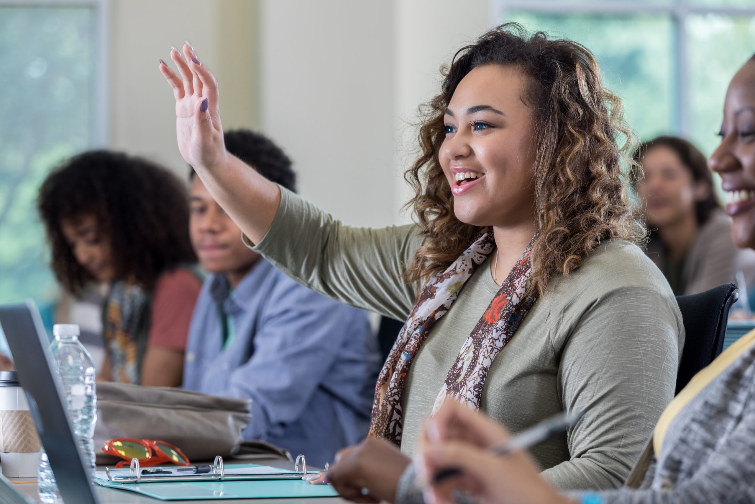 Adult college student raising their hand in class