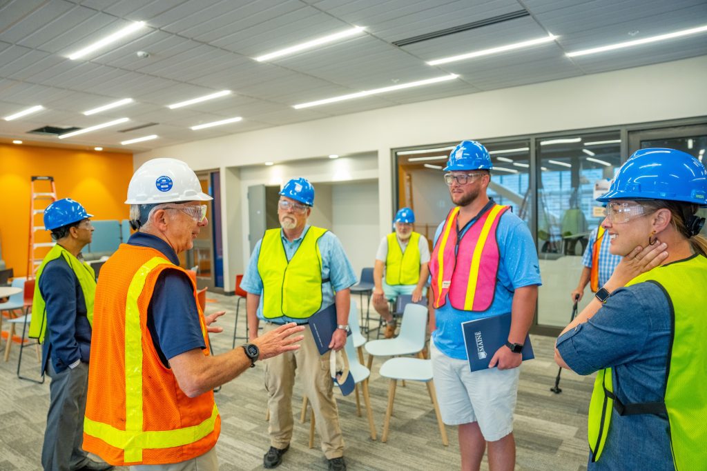 People wearing. hardhats in an engerring warehouse