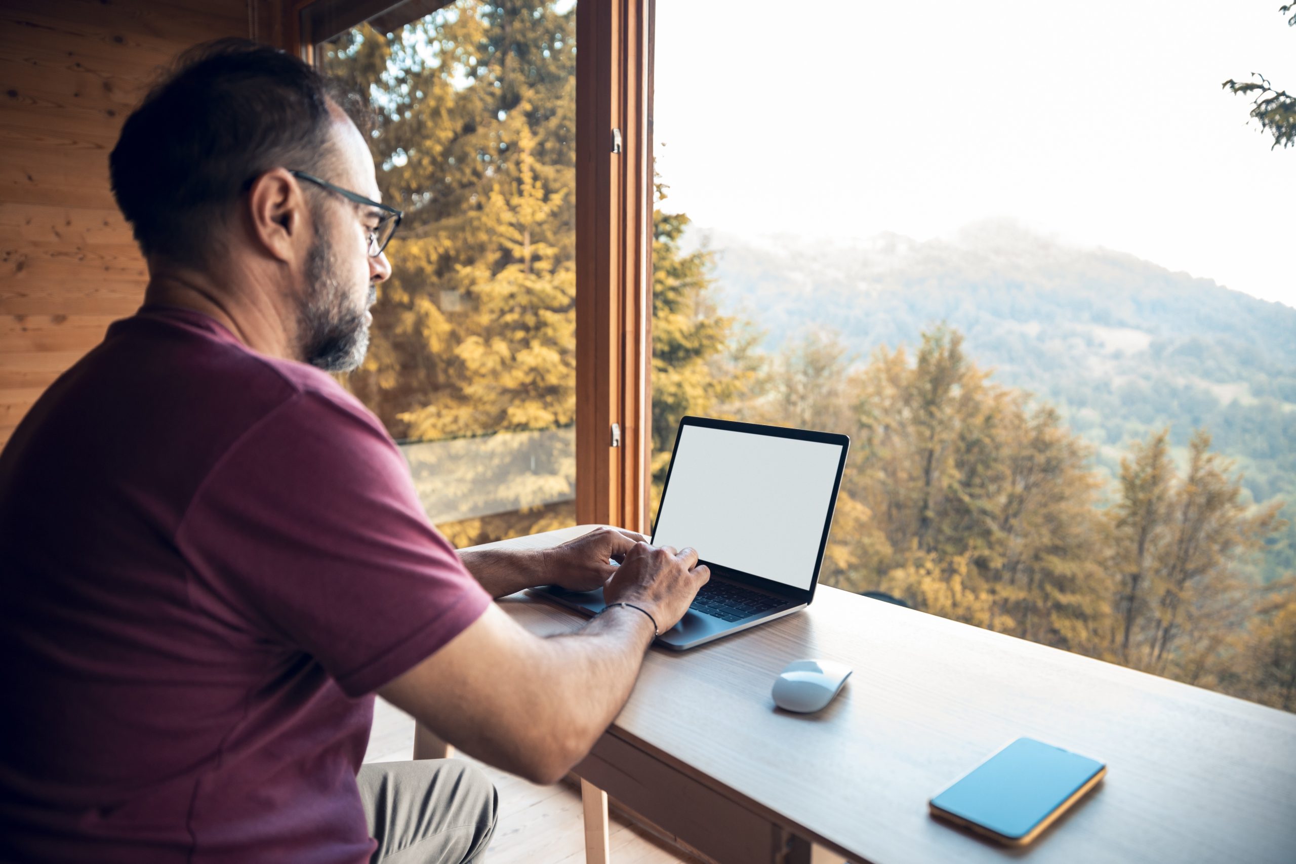 Person working on a laptop in a cabin in the woods