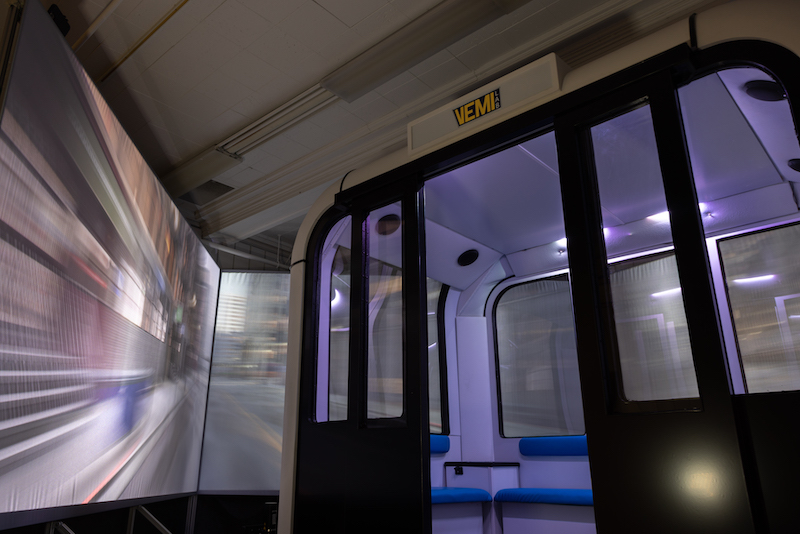 VEMI's autonomous vehicle simulator with a blurry city view on the surrounding screens.