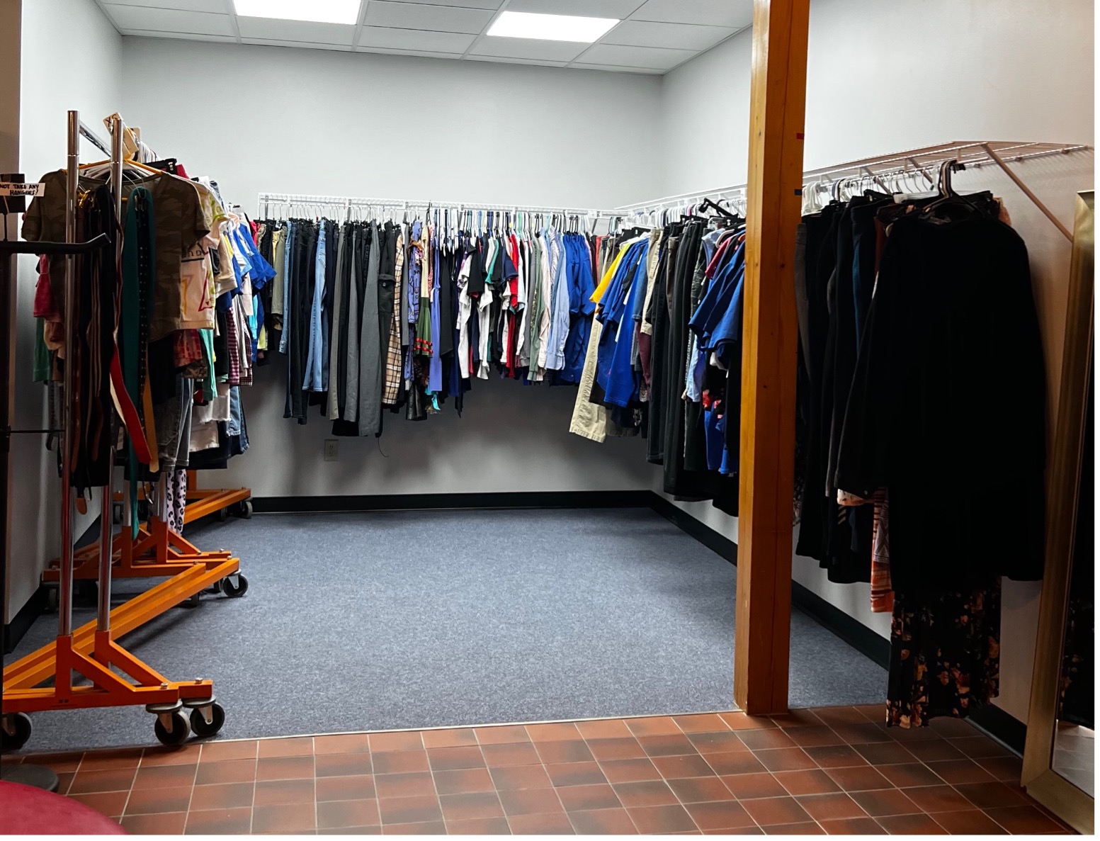 View of the clothing room at the BBE. Clothing hung from racks on the walls and free standing racks