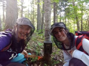 Graduate student and student field technician setting up a camera trap.