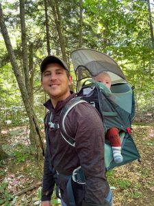 Portrait of Adam on a hike with an infant in a carrier on his back