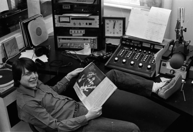 WMEB DJ from 1980s on air in studio A with record in hand.