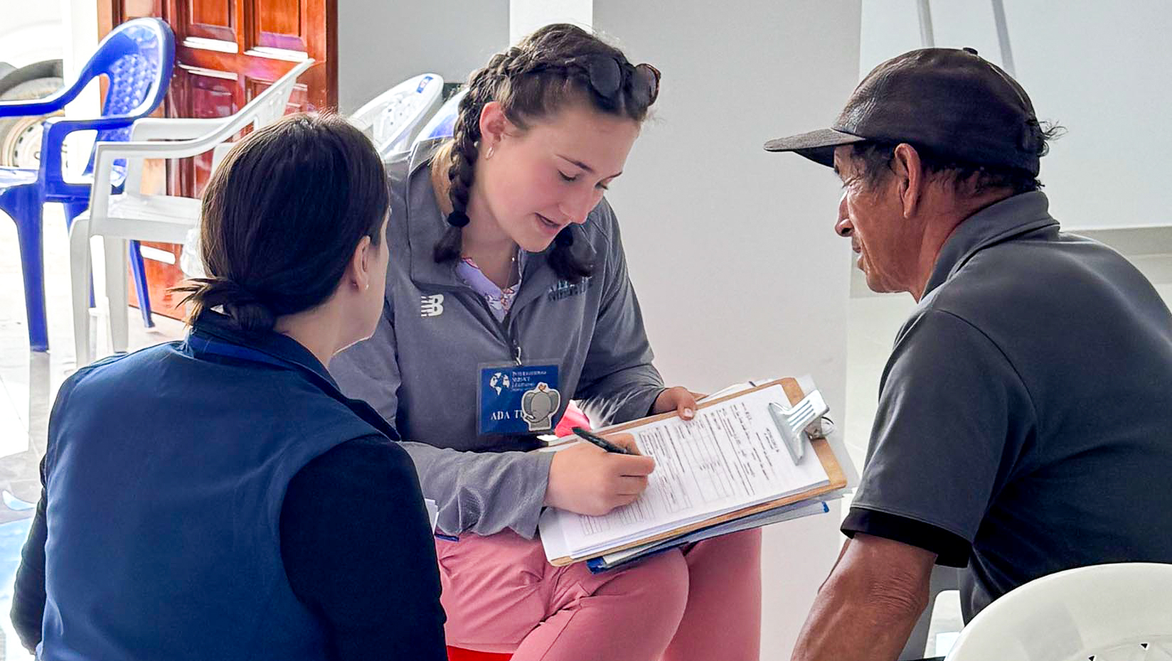 A photo of three people, on of whom is filling out a form.