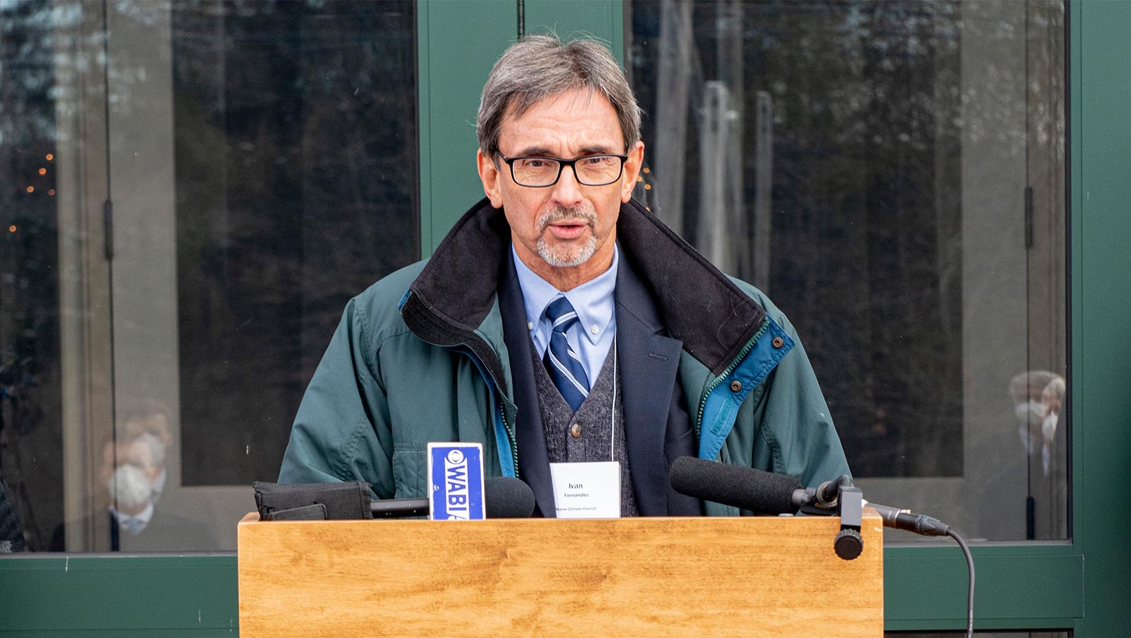 A photo of Ivan Fernandez speaking at a podium outside.