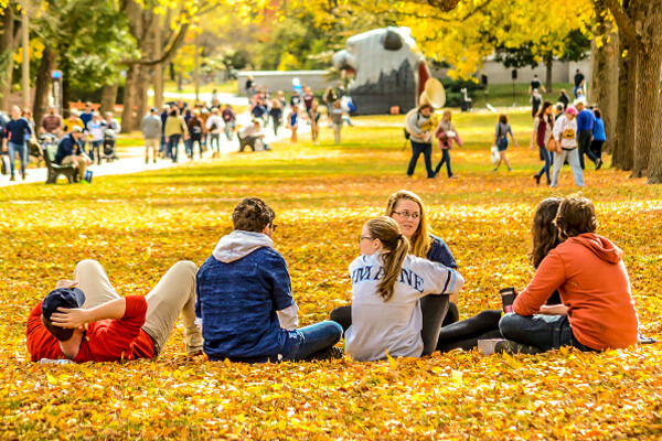 Students sitting on the mall surronded by fall leaves
