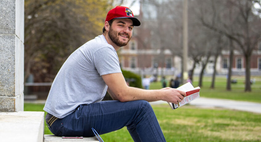 Male student sitting on steps of Boardman Hall