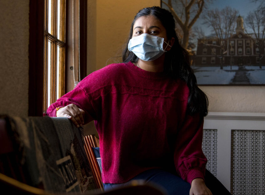 Woman wearing a mask sitting in a room near a window