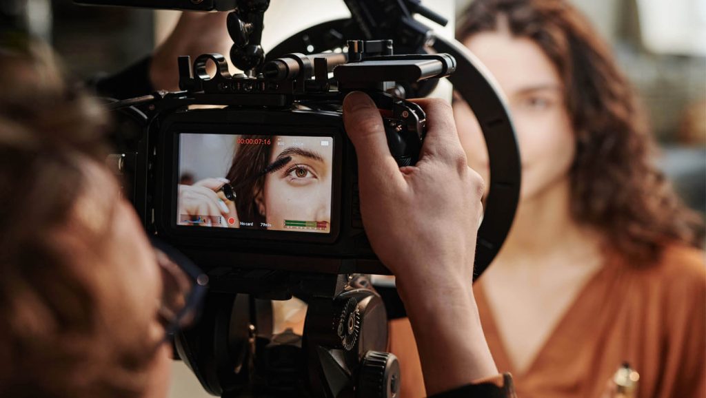 A photo of a woman putting on makeup in front of a camera