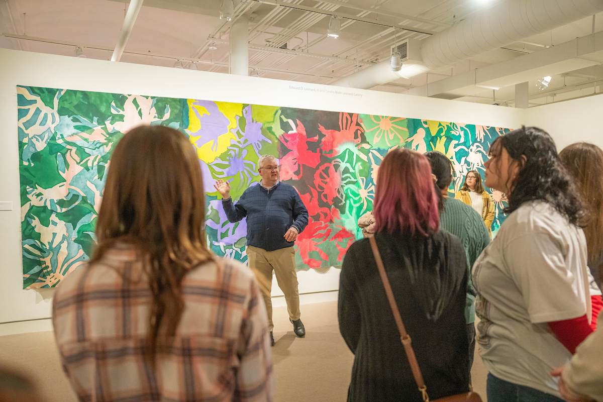 Honors students circle around an art exhibit