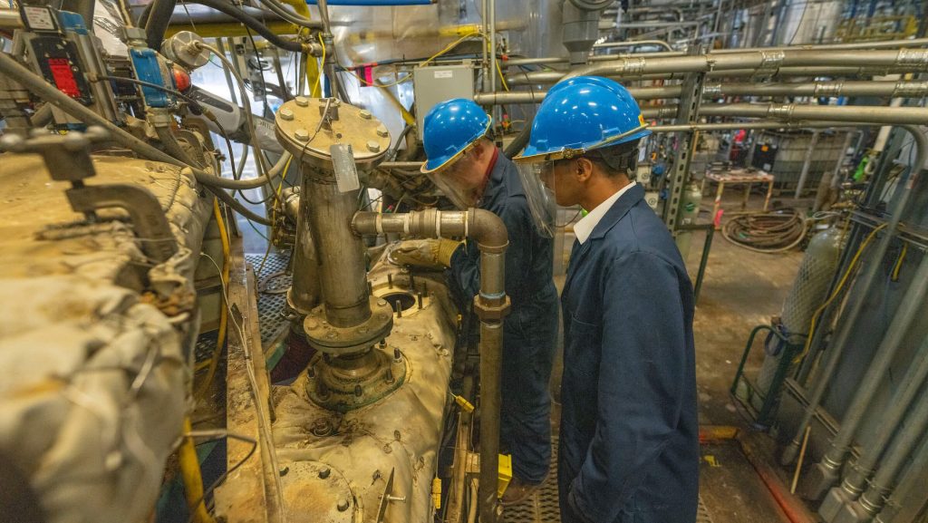 A photo of two people in a pilot plant looking at machinery