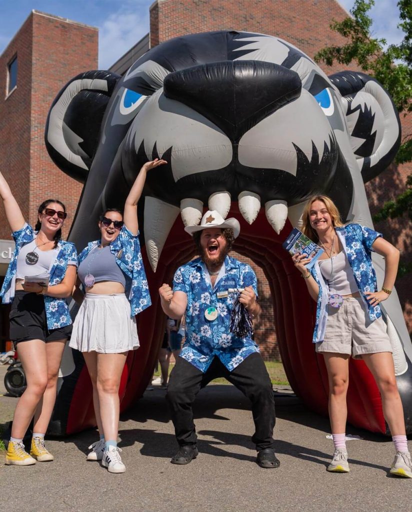 A photo of happy people in front of UMaine's inflatable bear head