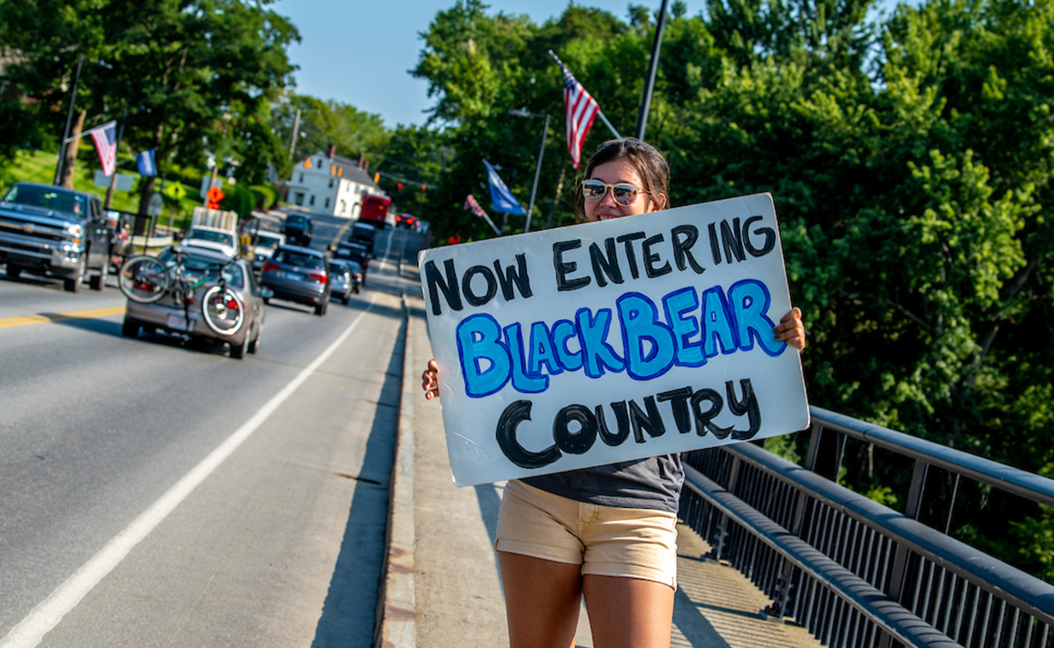 A photo of a student holding a sign that reads "Now Entering Black Bear Country"