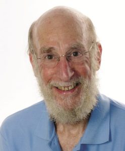 A smilling older man (Doug Allen) with a white beard and glasses in a baby blue polo shirt.