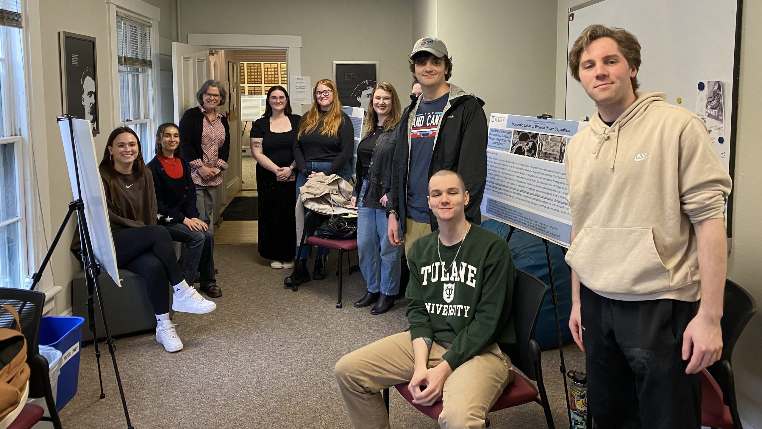 A collection of students and a professor smiling around posters they used to present their projects. 